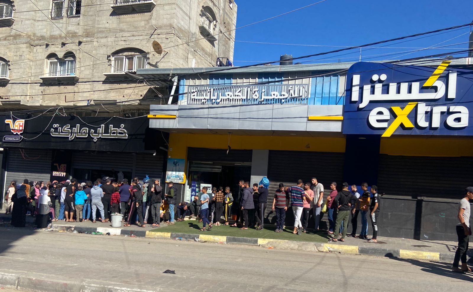 People standing in line outside of a bakery in rafah