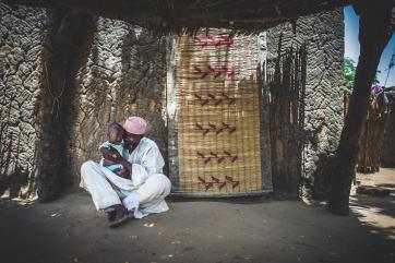 Alhaj holding a baby outside his home