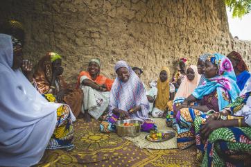 A group of people sitting together while someone prepares food.