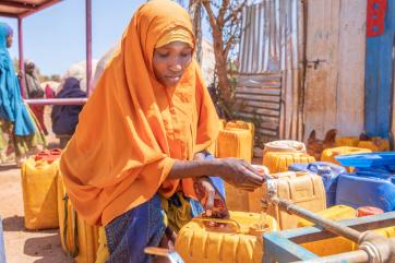 A person filling a jerry can with water.