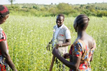 John sanya, project officer for mercy corps in the yumbe district, talks with the members of unit business group in their sesame fields.