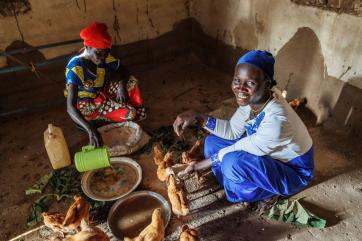 Two people feeding chickens.