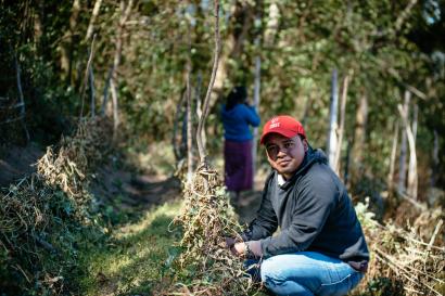 Man in guatemala kneeling in a field looking at the camera