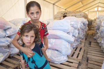 Muthana (6, bottom) and her sister Mazin (13, top) receive a household kit at a Mercy Corps distribution at the Jeddah displacement camp. In response to the crisis, Mercy Corps has distributed more than 18,000 kits benefiting more than 81,000 people.